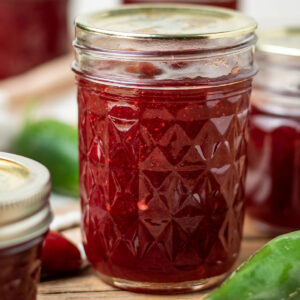 Jar of cranberry pepper jelly with fresh jalapenos.