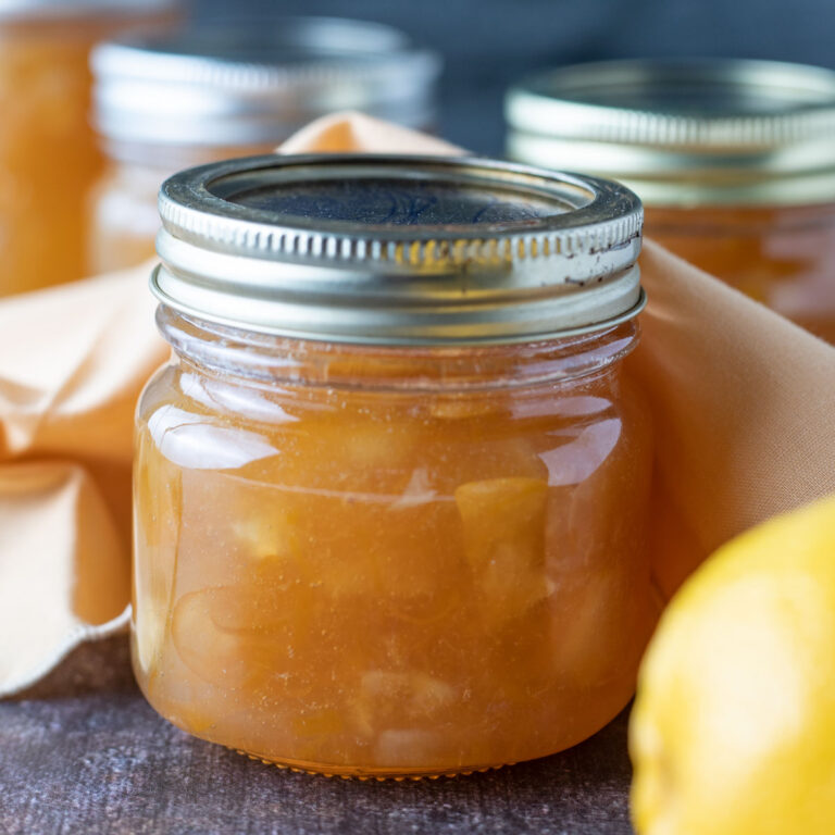 Jars of lemon marmalade with a fresh lemon.