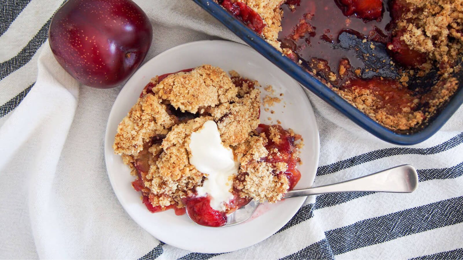 plum crumble on a white plate with ice cream.