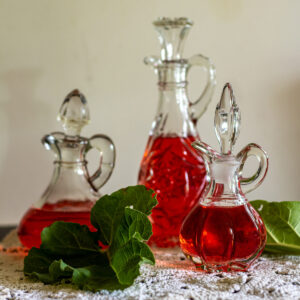 Three antique cruets filled with rhubarb vinegar.