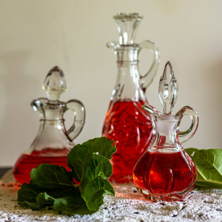 Three antique cruets filled with rhubarb vinegar.
