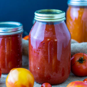 Jars of tomato sauce with fresh tomatoes.