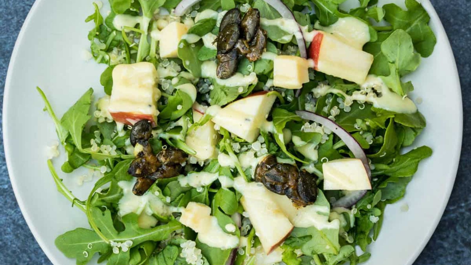 Top view shot of Arugula Salad with Apples and Quinoa in a plate.