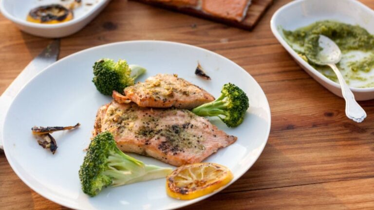 Grilled salmon with pesto on a plate.