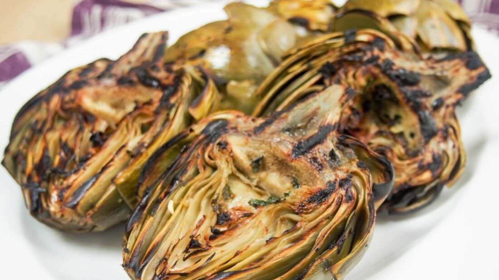 Close up shot of grilled artichokes on plate.