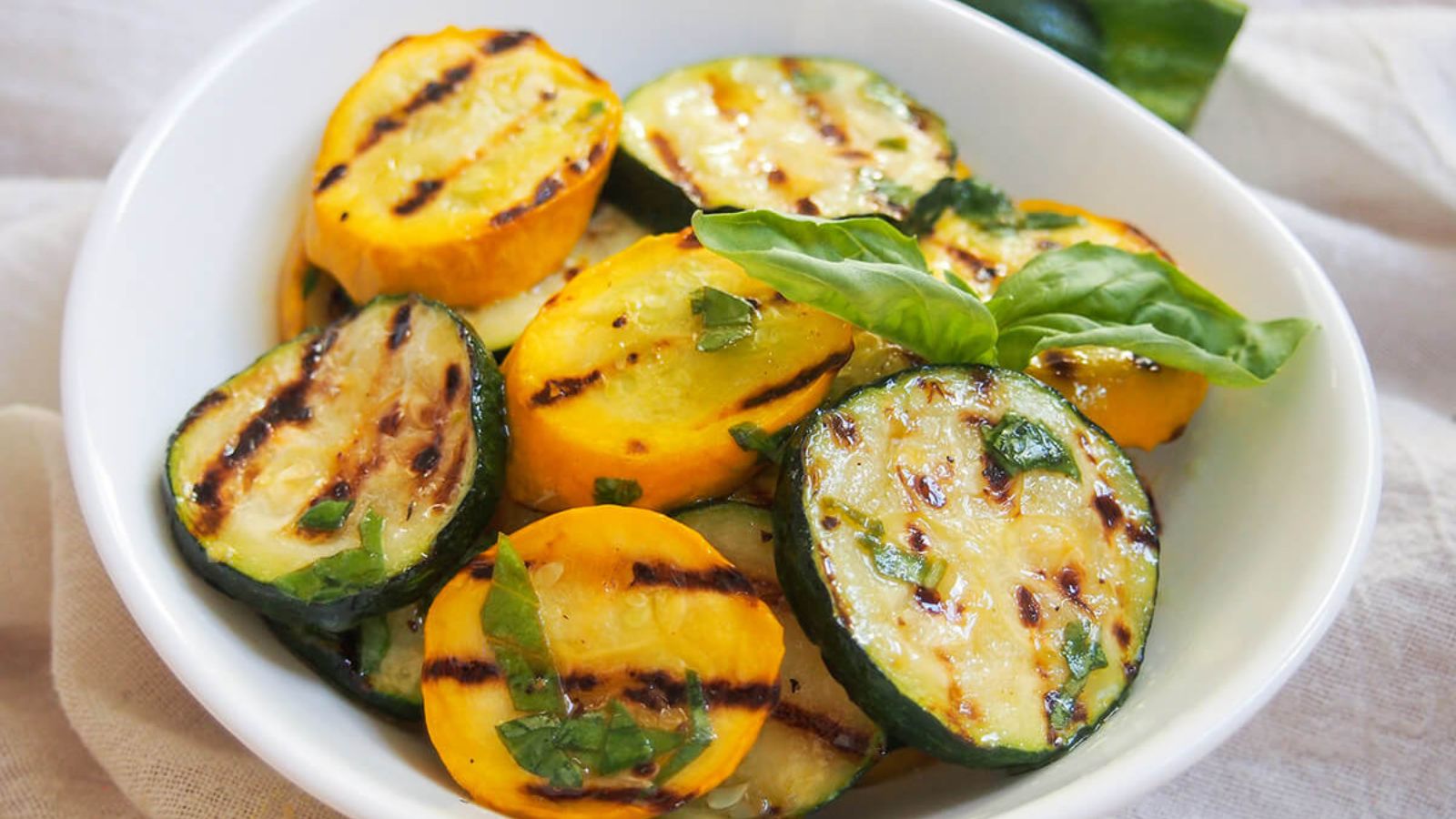 Marinated grilled zucchini in a bowl.