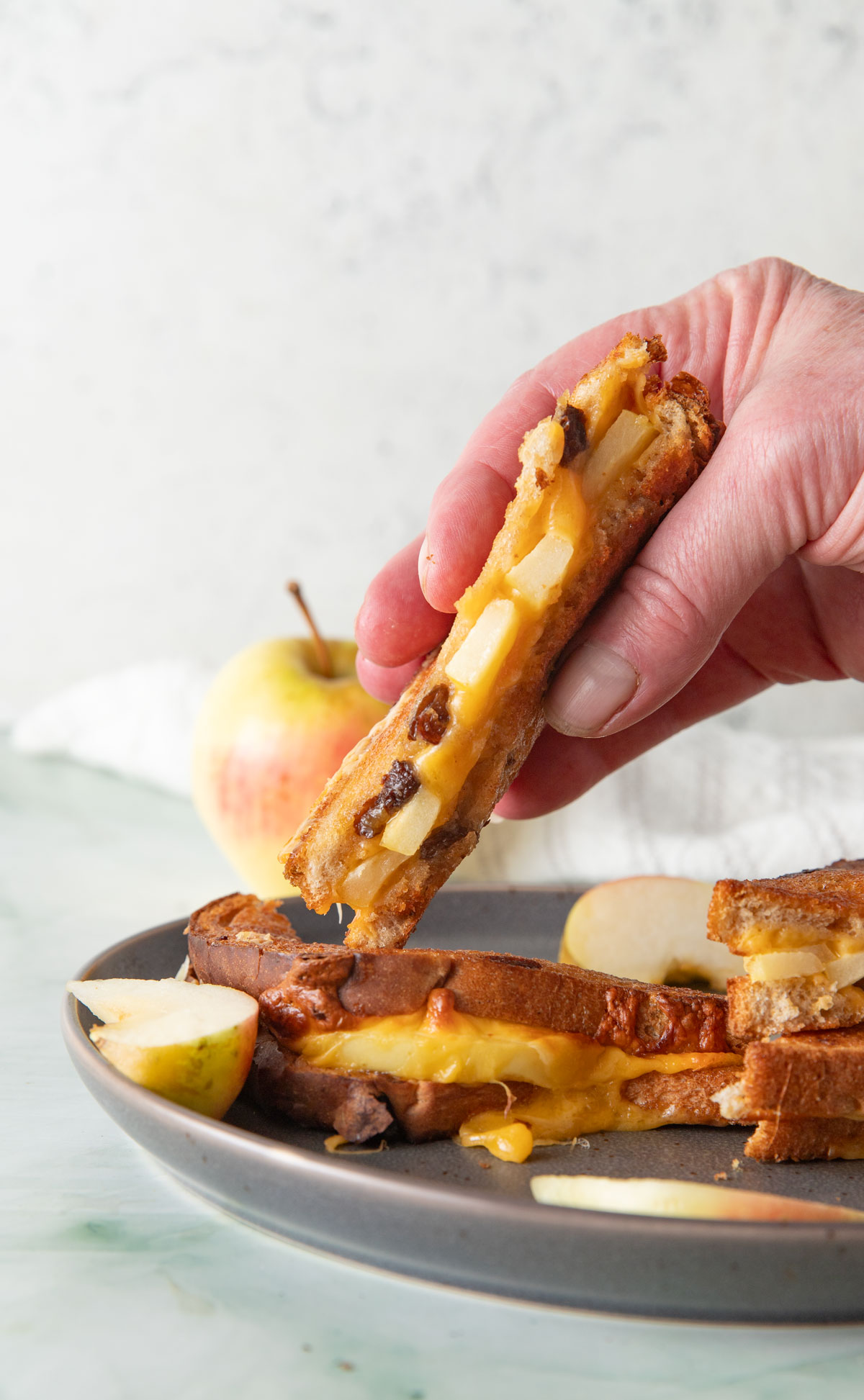 Woman's hand holding half of a grilled cheese sandwich.
