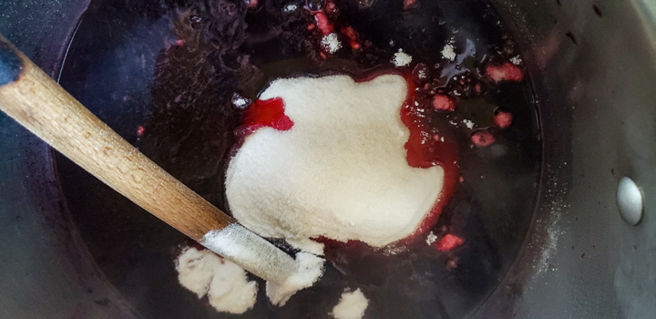 Sugar mixture added to a pot with cherries.