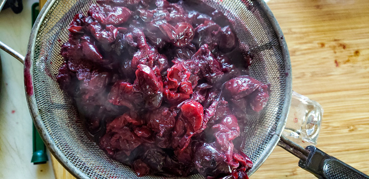 Pitted cherries in a strainer.