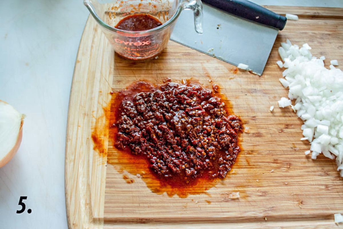 Chipotle peppers and adobo sauce chopped up on the cutting board.