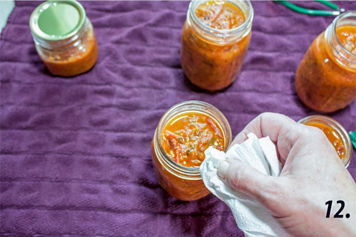 Wiping the rims of the jars with paper towel.