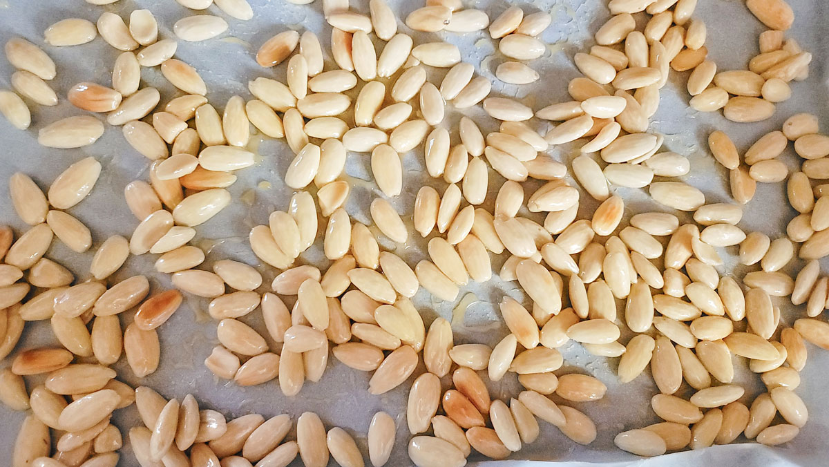 Almonds spread out on the parchment paper.
