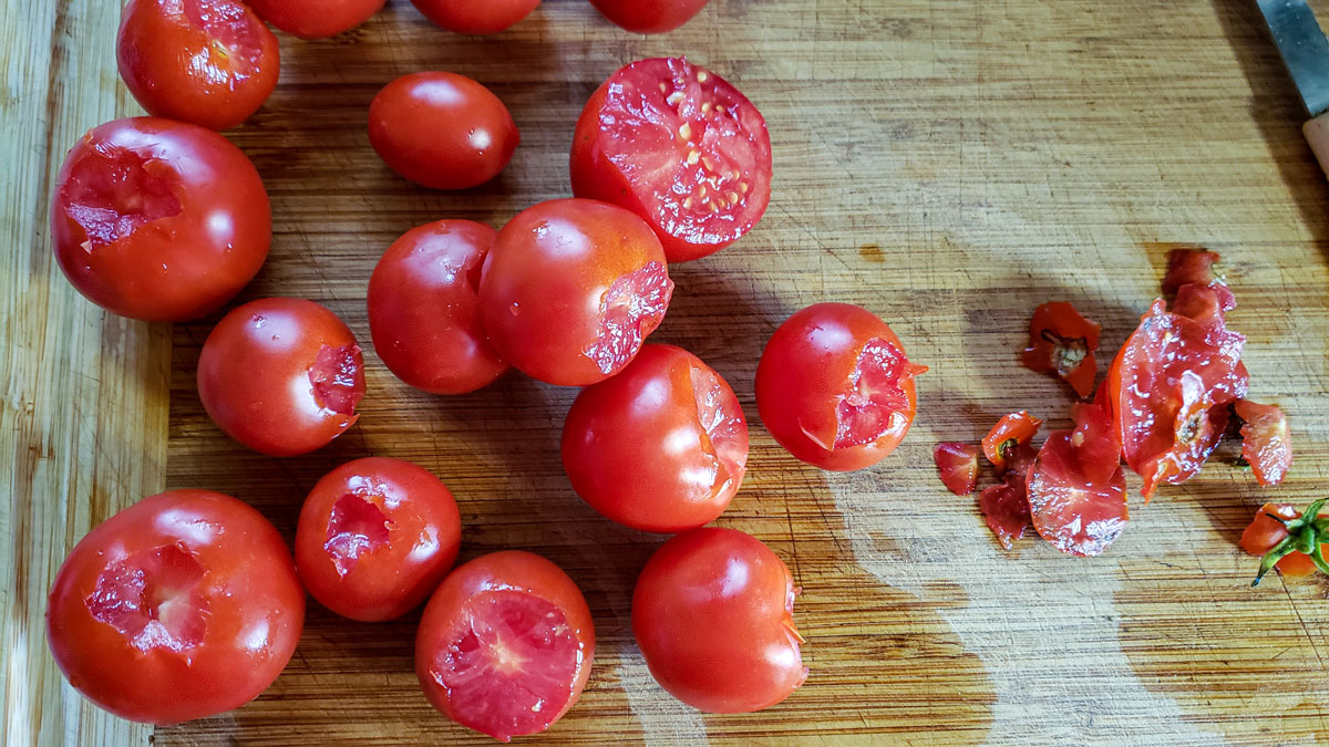 Trimmed tomatoes on a wooden cutting board.