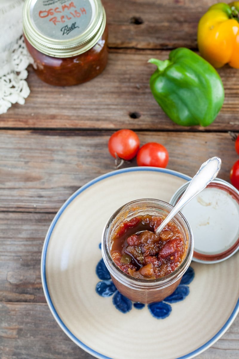 Open jar of Oscar Relish on On beige plate with blue flowers on antique barn wood table.