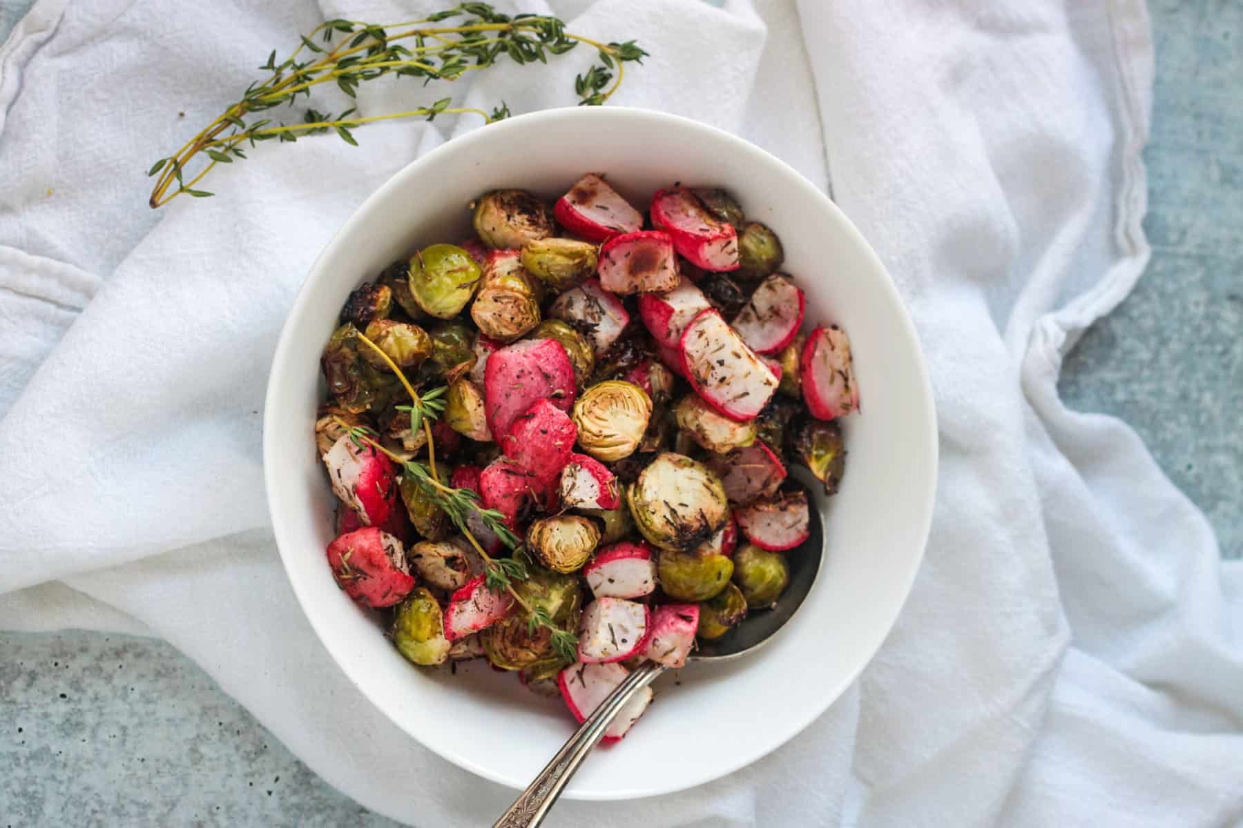 White bowl filled with roasted radishes and Brussels Sprouts.