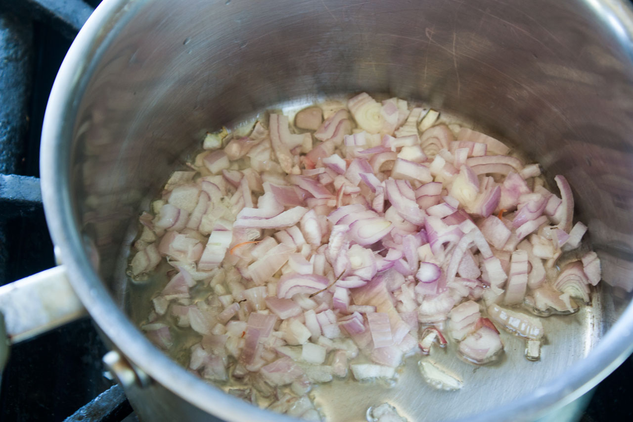 Shallots cooking in a pot with olive oil.