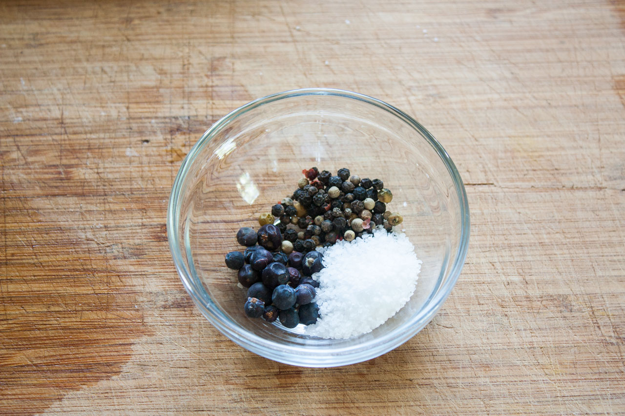 Peppercorns juniper berries and salt in a small bowl.