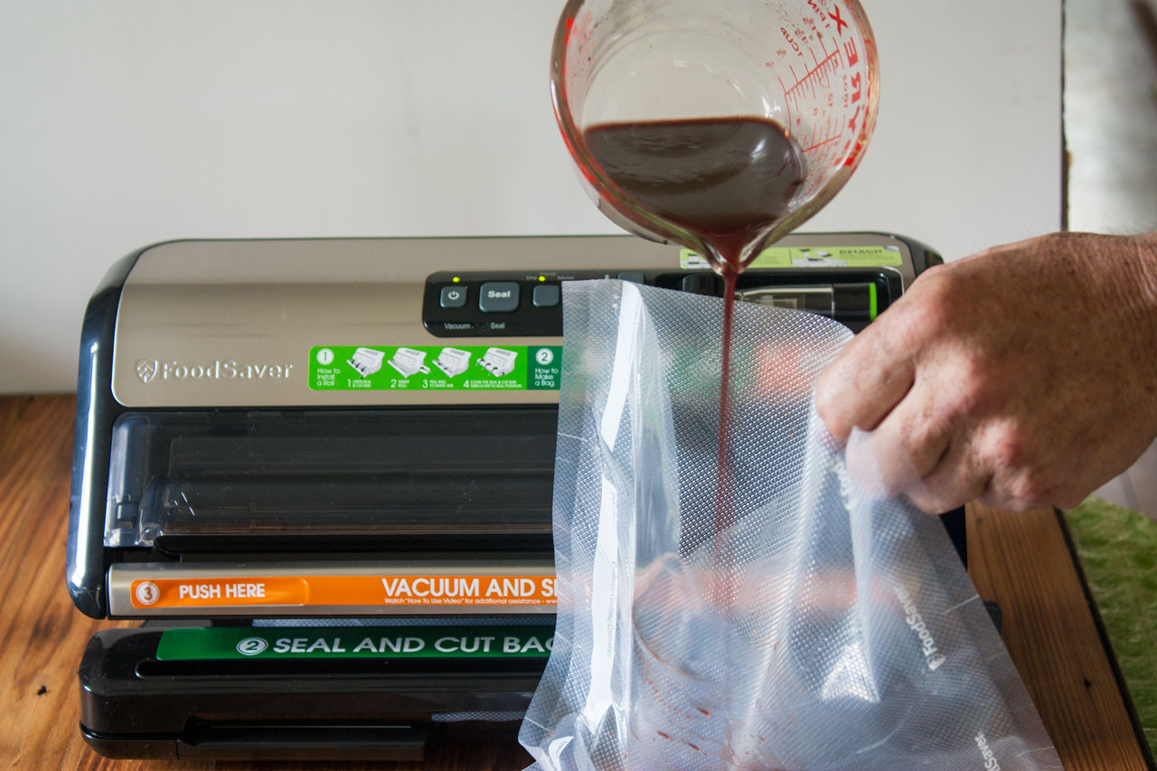 Pouring marinade in a vacuum saver bag with the venison.