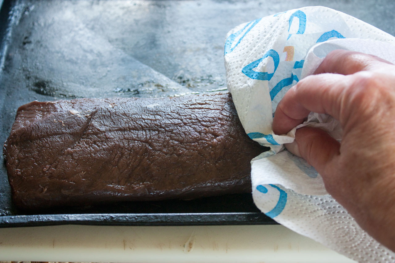 Patting the roast with paper towel to dry.