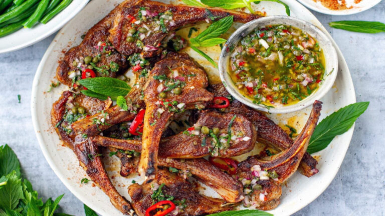 Spiced lamb cutlets with colorful sauce.