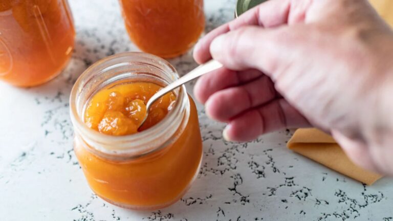 Spoon in jar of apricot jam.