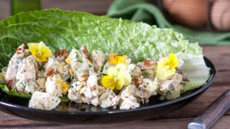 Chicken salad in a romaine lettuce leaf garnished with edible violets.