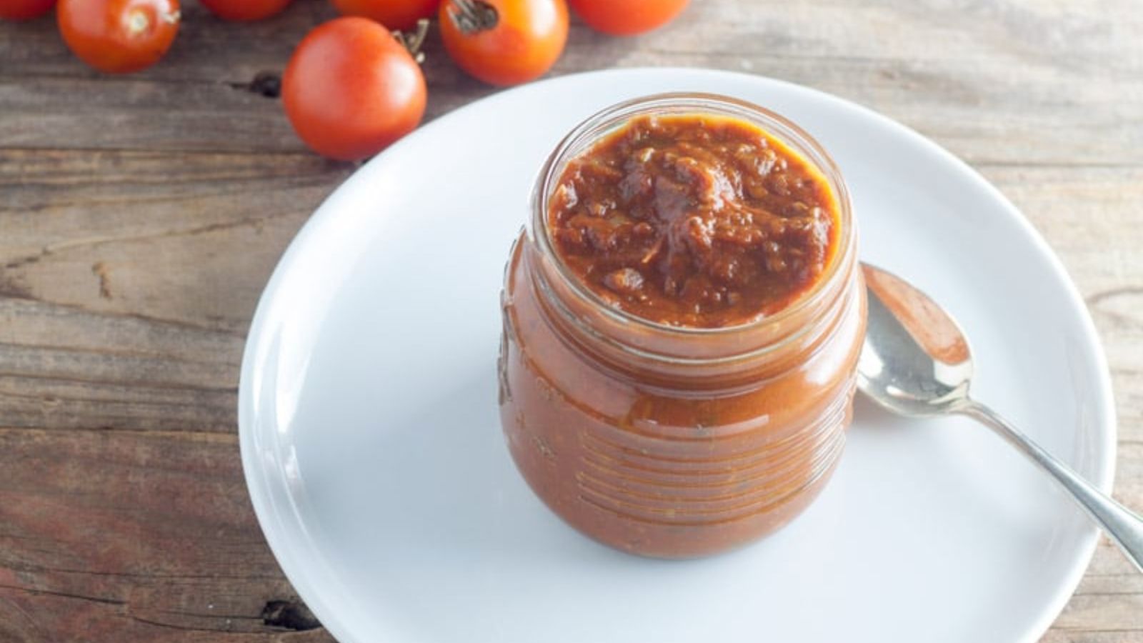 Open jar of salsa on white plate.
