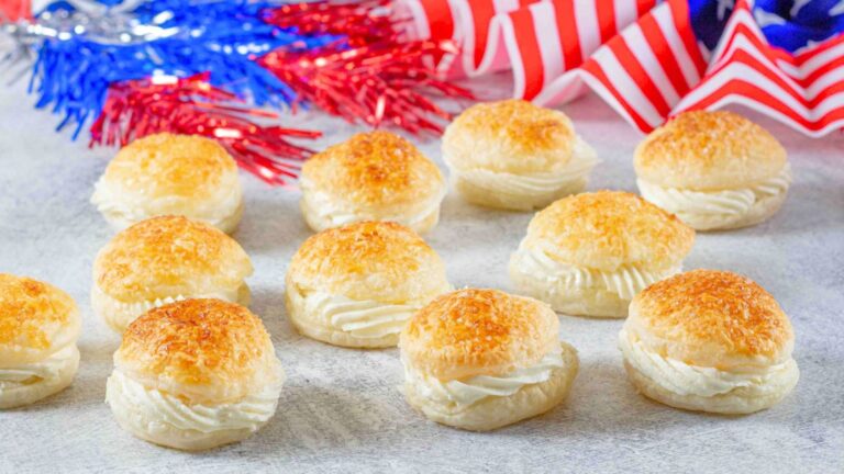 Cream filled puffed pastry with fourth of July decorations in the background Pinterest image with text overlay.