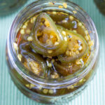Closeup of opened jar of candied jalapeños, showing sliced peppers.