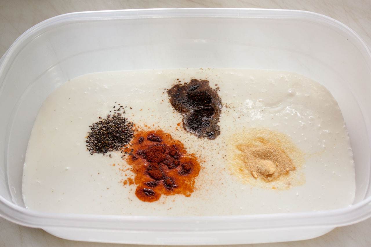 Spices added to buttermilk in a large container.