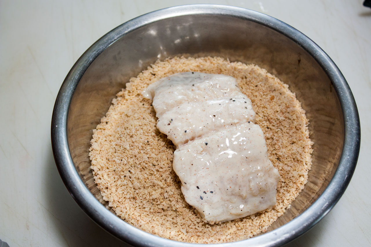Fish filet added to the panko mixture in a medium bowl.