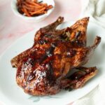 Whole roasted duck with crispy skin and cherry glaze on a platter