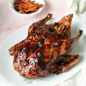 Whole roasted duck with crispy skin and cherry glaze on a platter