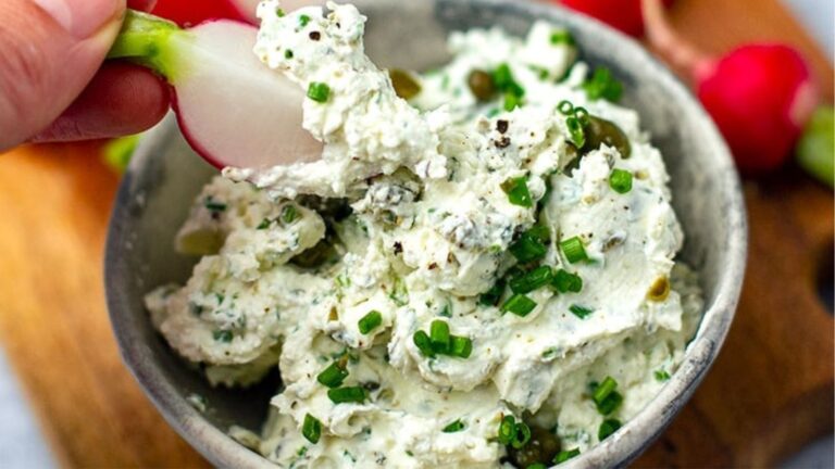 Woman's hand dipping a radish into cream cheese dip.