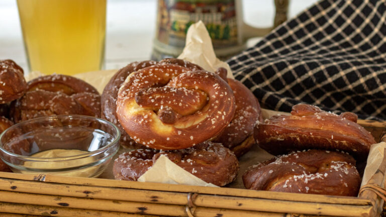 Pretzels in a basket with a glass of beer in the background.