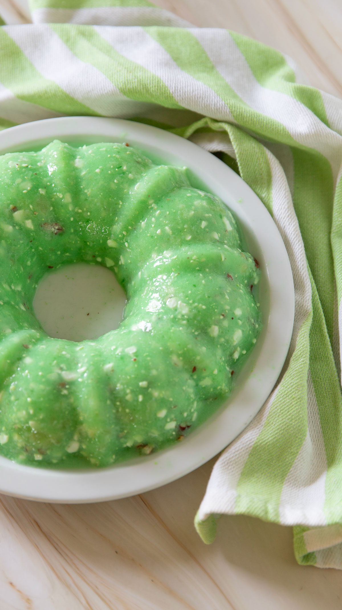 Green jello salad with a green and white striped kitchen towel.