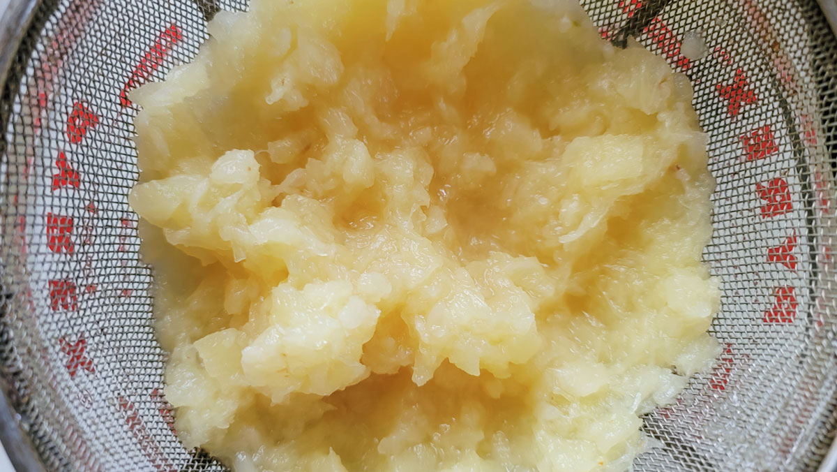 Crushed pineapple draining in a sieve.