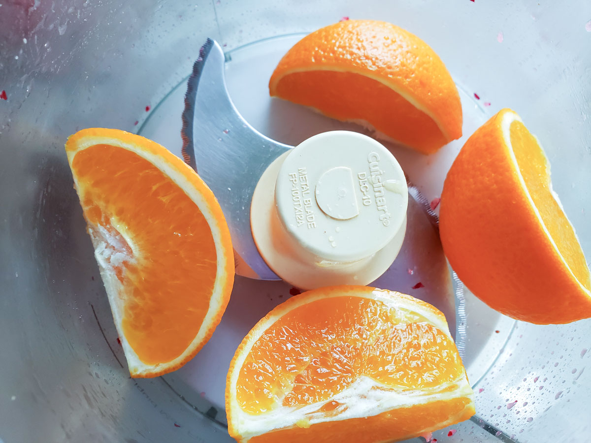 Quartered orange in the food processor bowl.