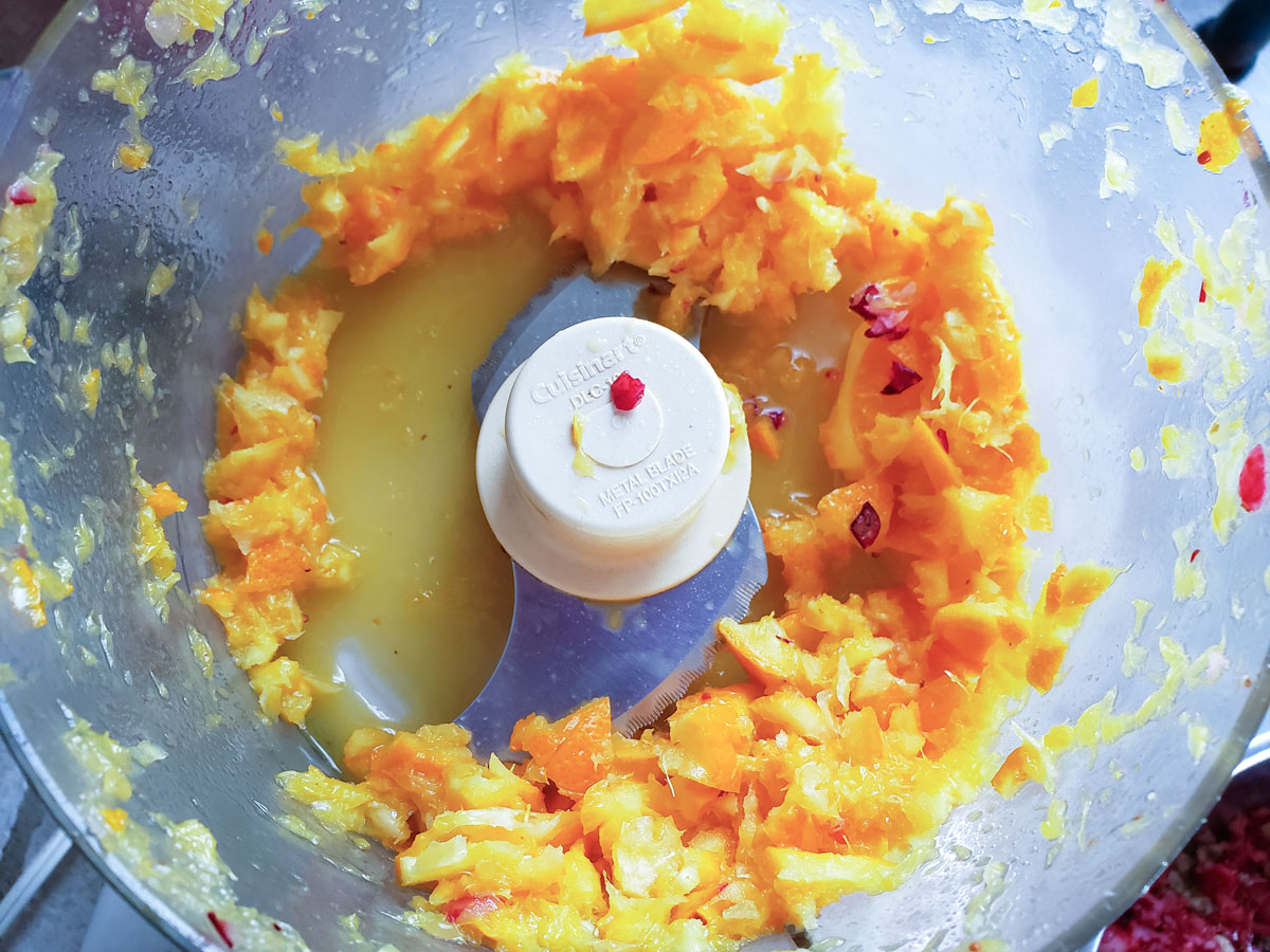 Chopped up orange in a food processor bowl. 