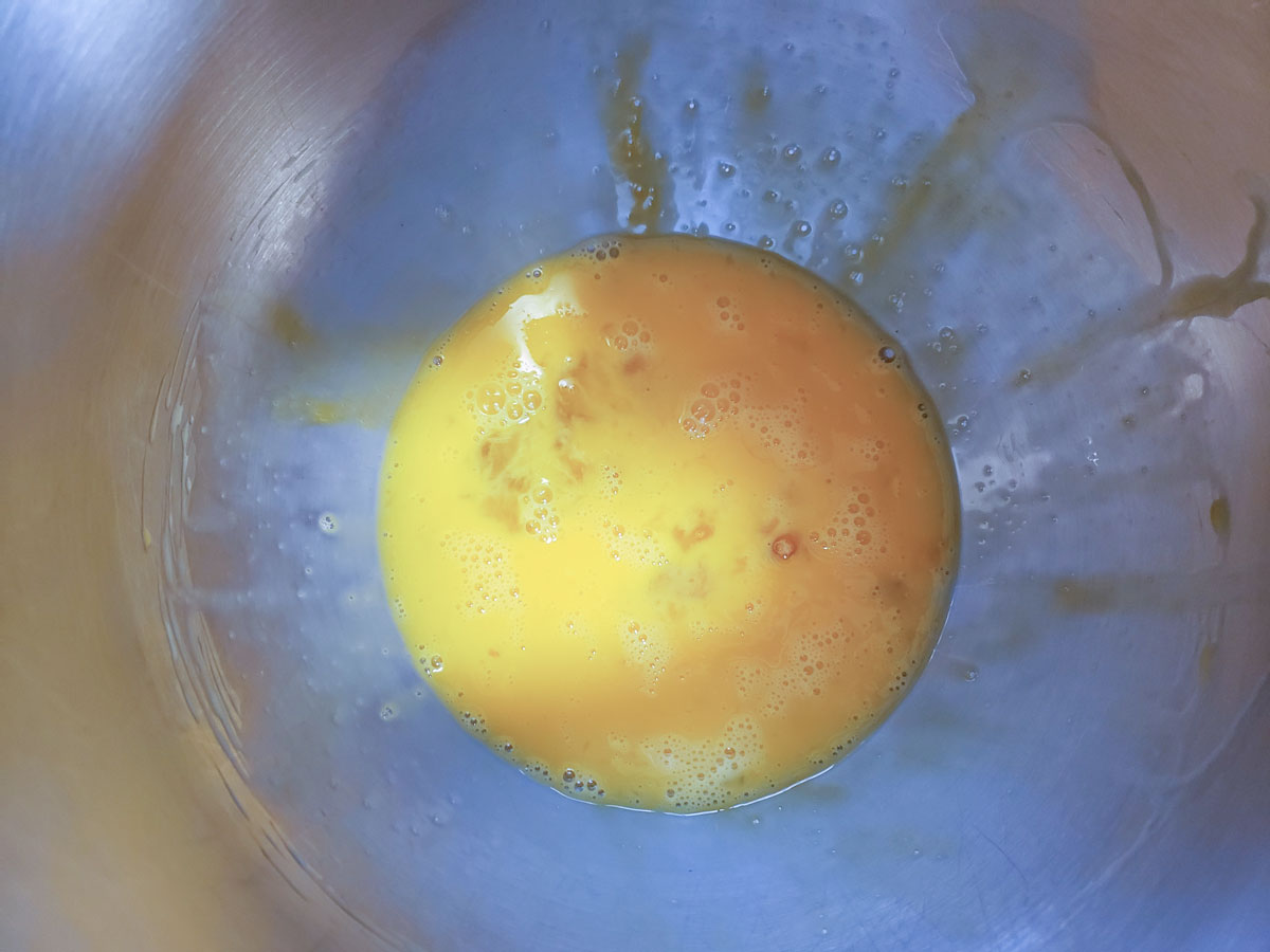 Beaten eggs in a mixing bowl.