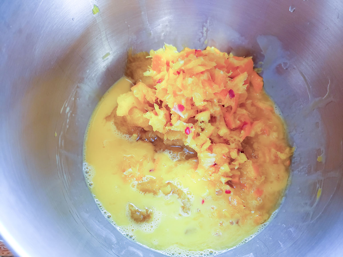 Pumpkin and orange added to the eggs in the mixing bowl.