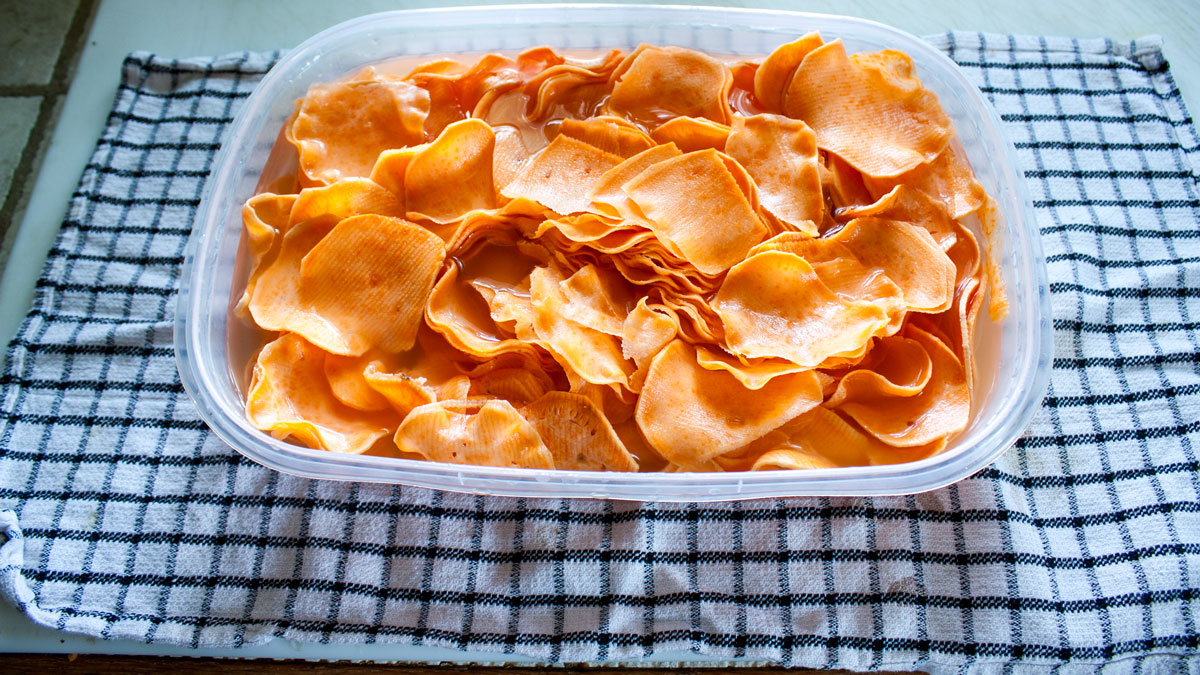 Thinly sliced sweet potatoes soaking in cold water in a large container.